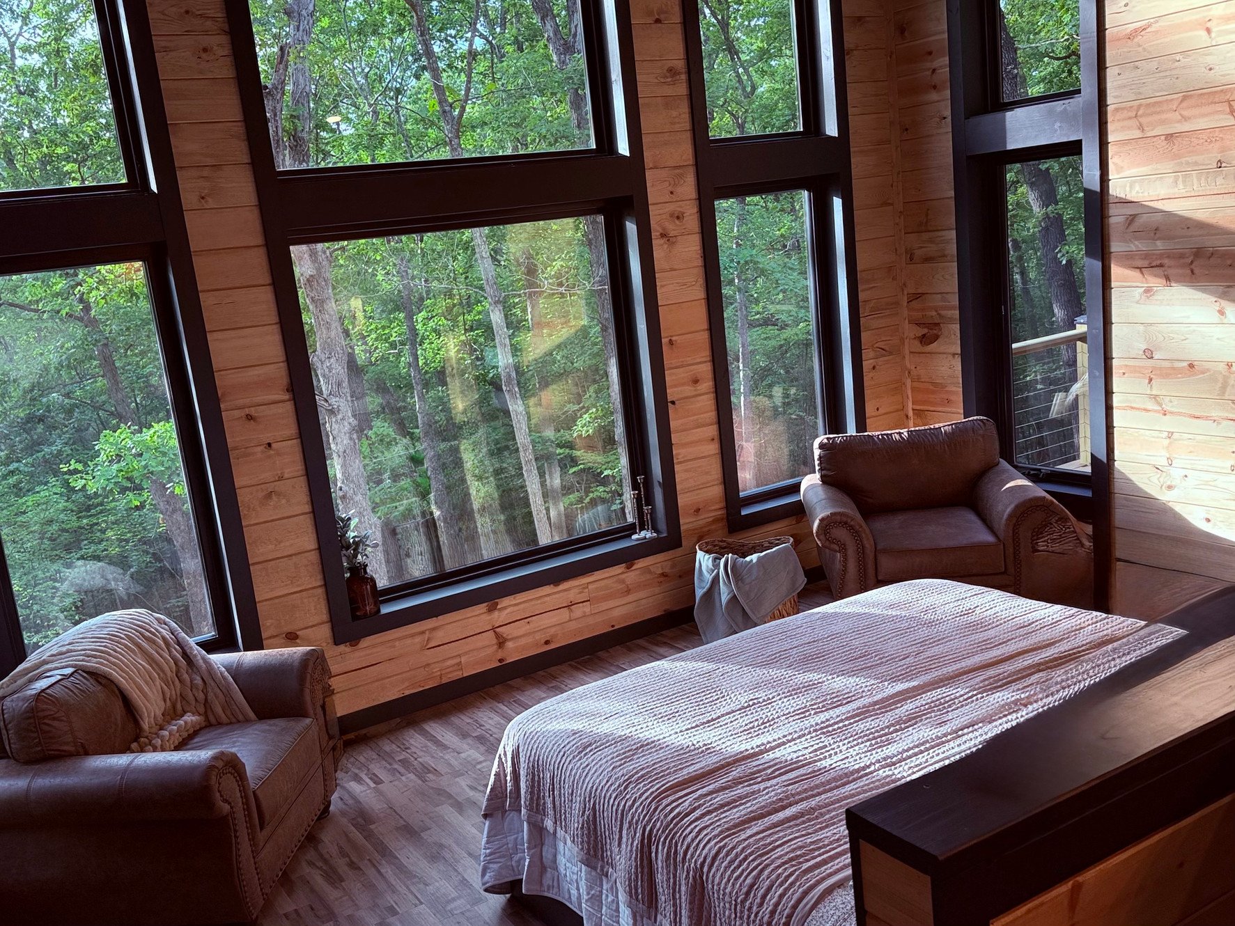 Cozy bedroom with forest view through large windows and wooden interior