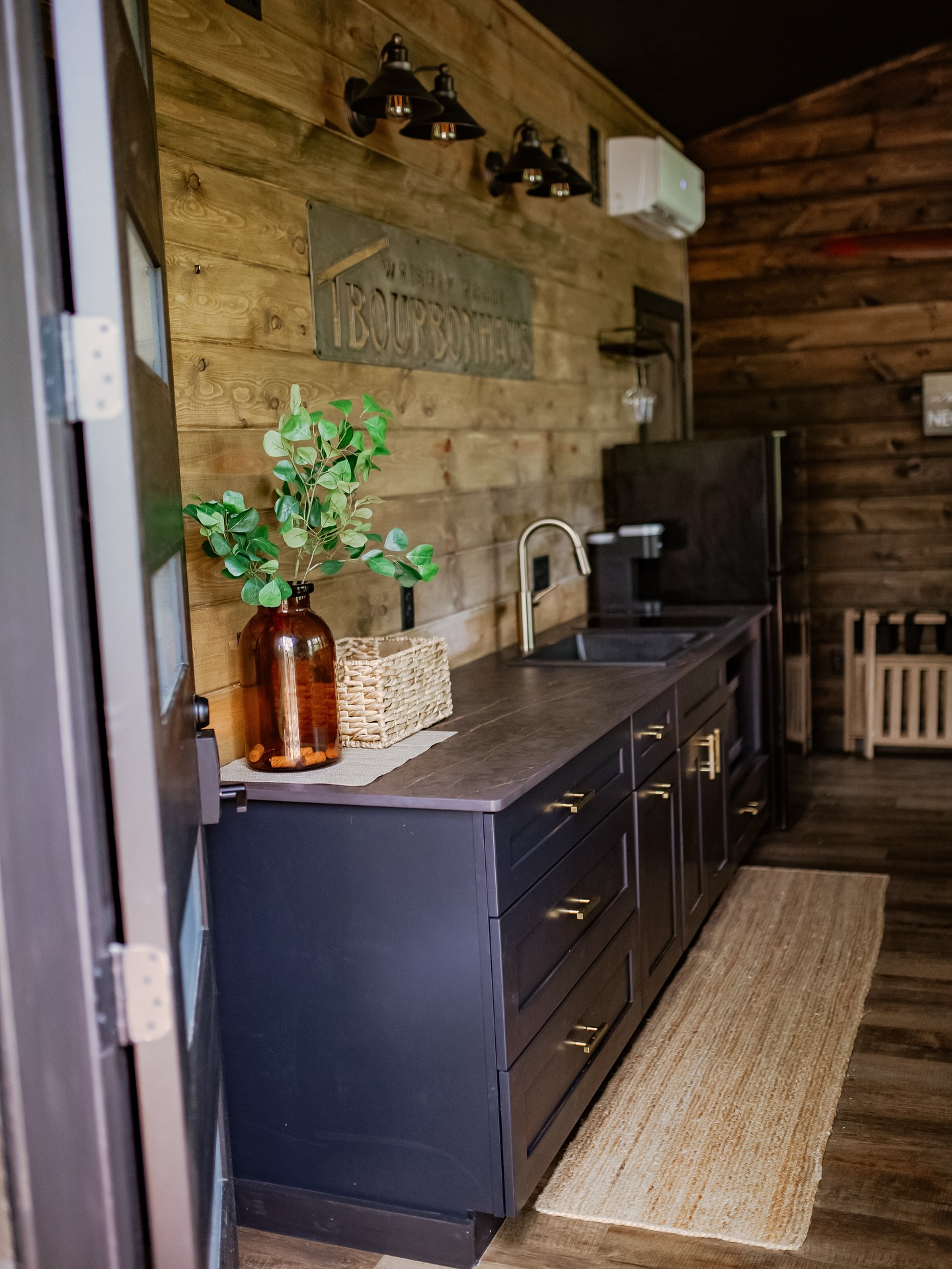 Rustic kitchen with dark cabinets, wooden wall, and green plant decor