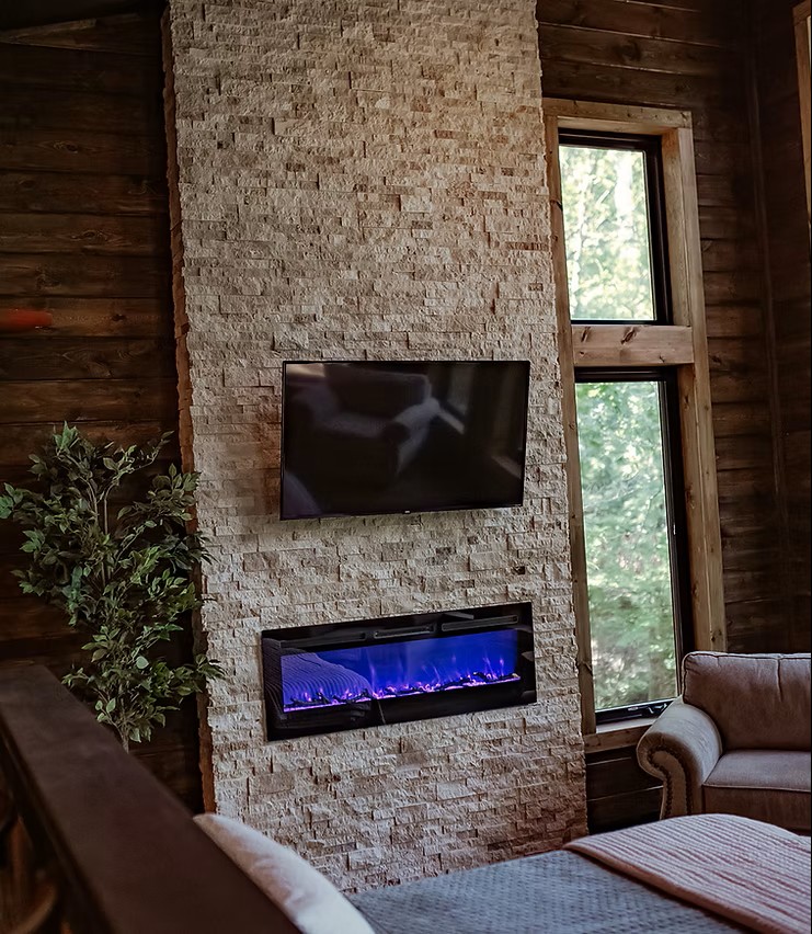 Stone fireplace with blue electric fire and mounted TV in rustic wooden room