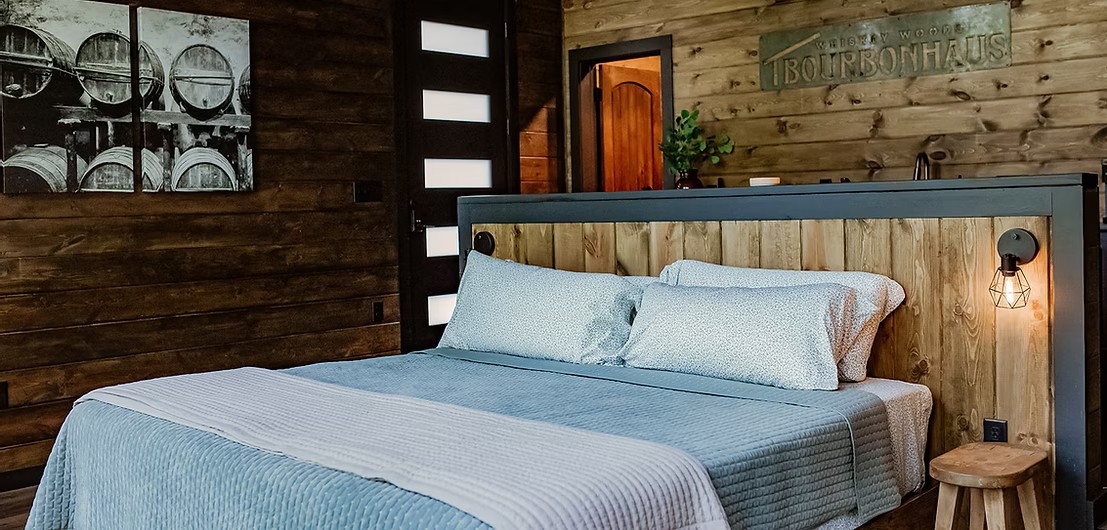 Rustic wooden bedroom with blue bedding and bourbon barrel art