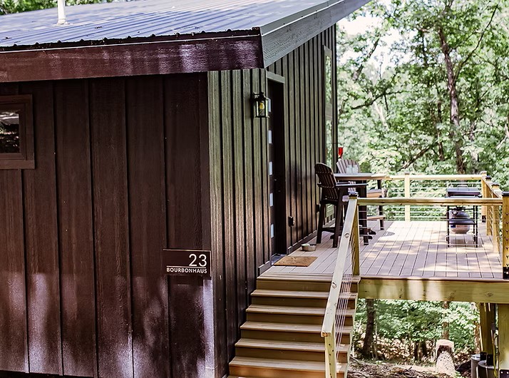 Wooden cabin number 23 with deck nestled in wooded forest setting