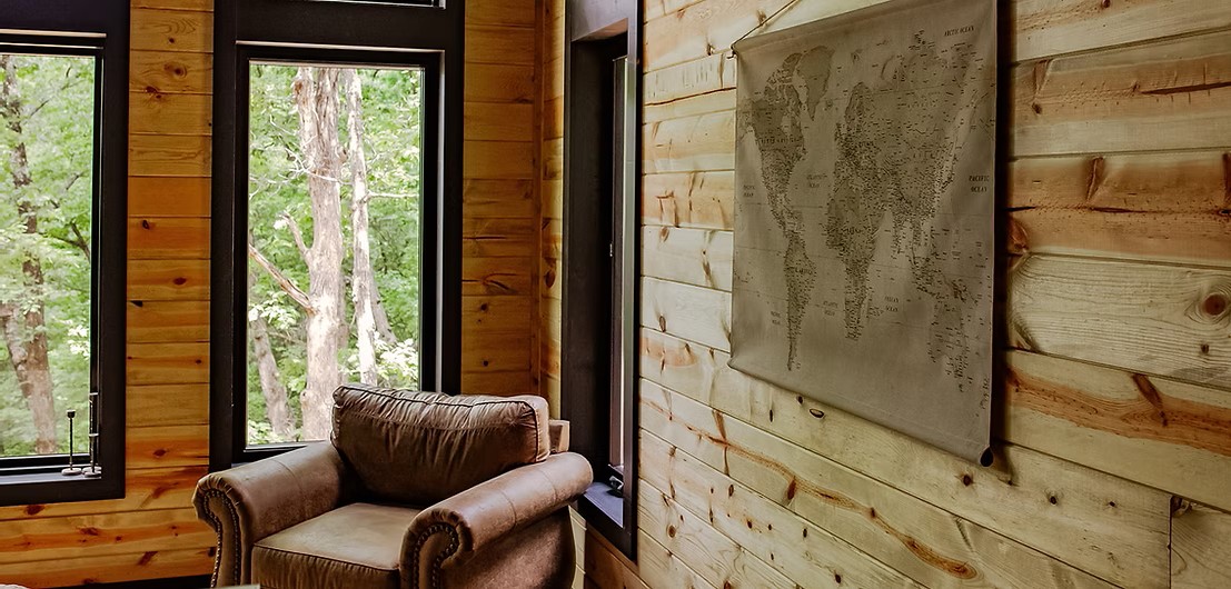 Cozy leather armchair near window with world map on wooden wall