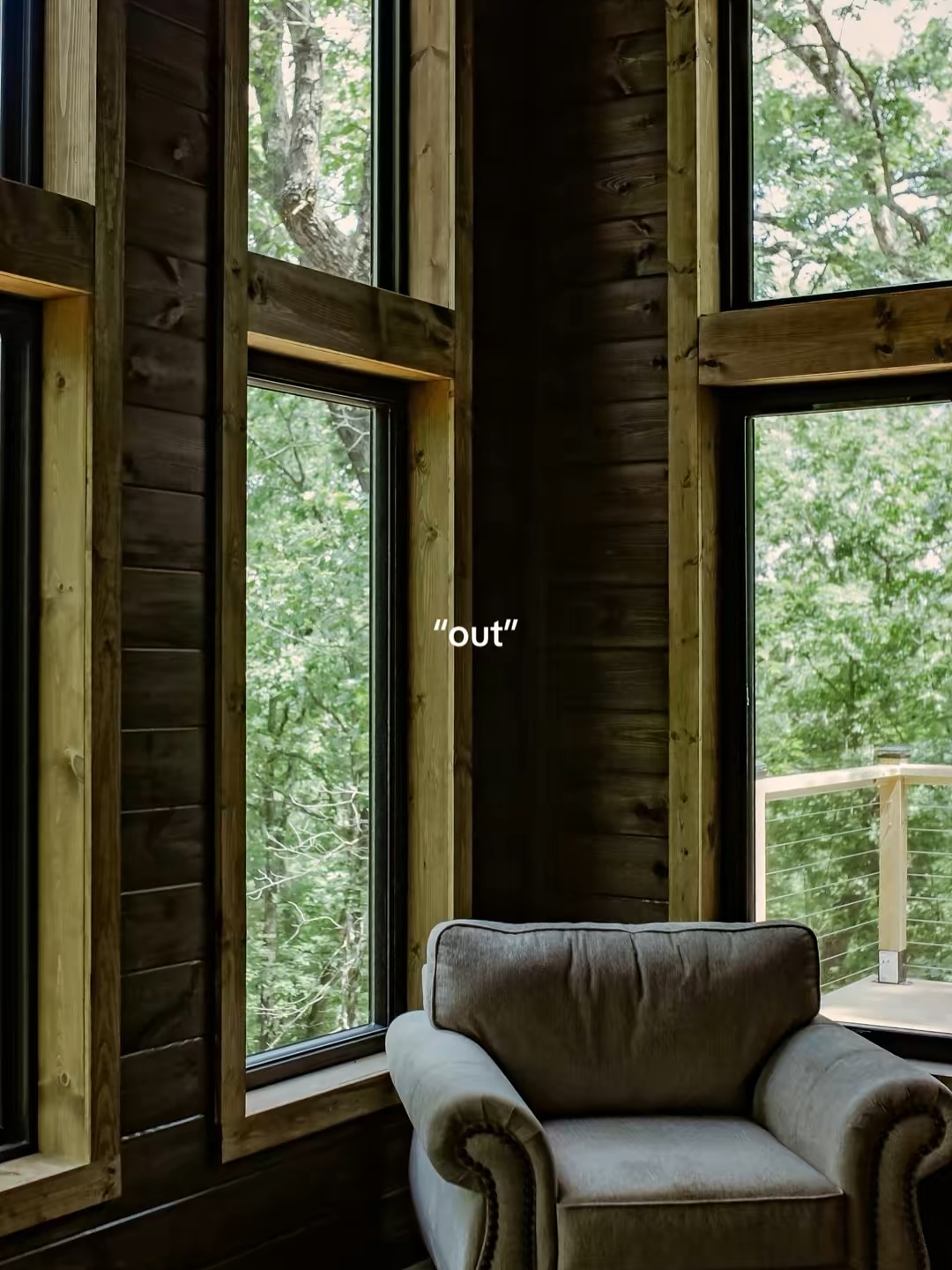 Cozy armchair by large windows overlooking lush green forest